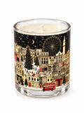 A scented candle  decorated with a festive Christmas London cityscape illustration featuring red double-decker buses,  and snow-covered landmark buildings and attractions